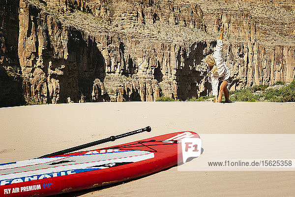 Eine Frau praktiziert Yoga auf einer Sandbank neben dem Colorado River  Grand Canyon National Park  Arizona  USA