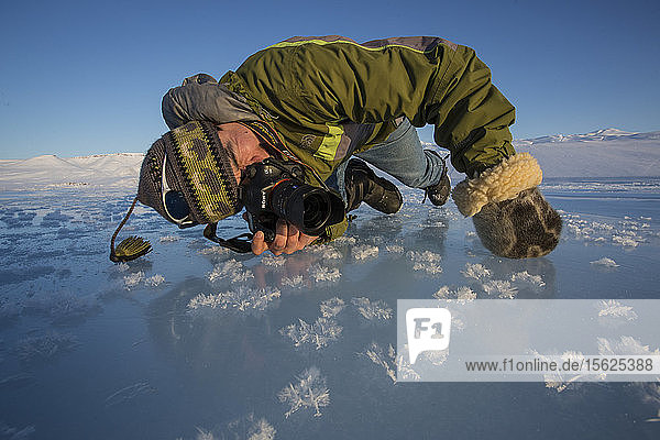 Ein Fotograf macht eine Nahaufnahme von Eisblumen/Kristallen an der Küste des Arktischen Ozeans außerhalb von Arctic Bay  Nunavut.