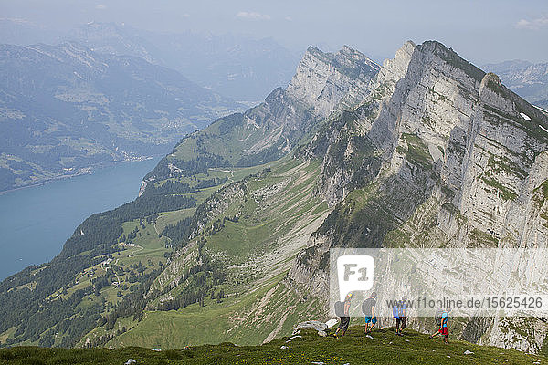 A group of base jumpers hiking in the Alps above Lake Wallen to find their next flight sight. Toggenburg Switzerland