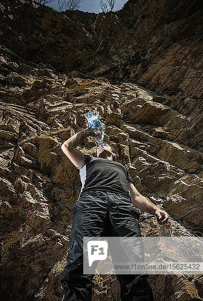 Wanderer trinkt Wasser aus einer Plastikflasche unter einem Felsen im Ort Sava Hermitage  Zentralserbien.