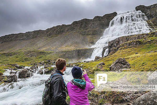 Ein Paar macht ein Foto am Dynjandi-Wasserfall  dem größten Wasserfall in den Westfjorden Islands