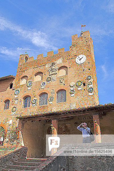 Ein Besucher macht ein Foto von der Terrasse des Palazzo Pretorio oder Vicariale  dessen Teile aus dem 13. Jahrhundert stammen. Der kürzlich restaurierte Wohnsitz der florentinischen Gouverneure hat eine malerische  mit Keramikwappen verzierte Fassade  und im Inneren sind verschiedene Fresken aus dem 13. bis 16.