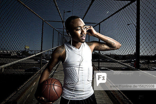A basketball player in athletic wear  walks down a footbridge in San Diego  California while listening to his headphones.