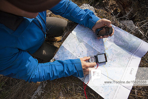 Mann benutzt Karte  Kompass und GPS  um beim Wandern zu navigieren
