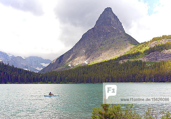 Many Glacier area  Glacier National Park: A lone kayaker braves incoming weather on Swiftcurrent Lake  Grinnell Point dominating the background.