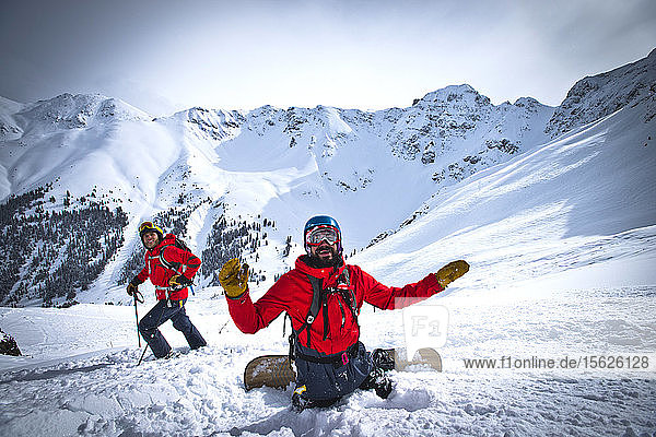 A skier and a snowboarder stop to watch their friends ski down Silverton Mountain in Colorado.