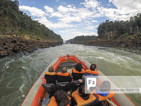 Tourists wearing life jackets sitting in inflatable raft during tour of Iguazu Falls National Park  Parana  Brazil