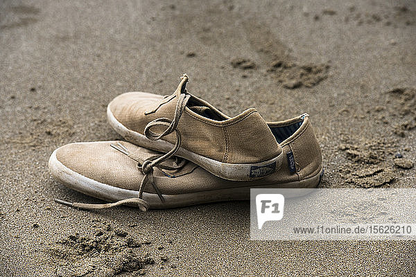 Ein Paar Schuhe  das am Strand im Sand liegt