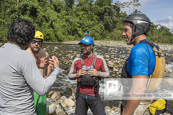 Photograph of men discussing safety briefing before departing on jungle river stand-up paddleboard expedition  Manu National Park  Peru