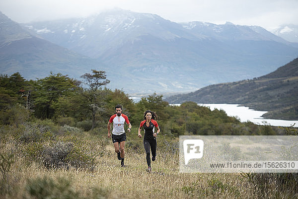 Front view shot of man and woman trail running in Torres del Paine National Park  Magallanes Region  Chile