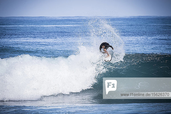 Totale Aufnahme eines einzelnen Jungen im Neoprenanzug beim Surfen im Meer
