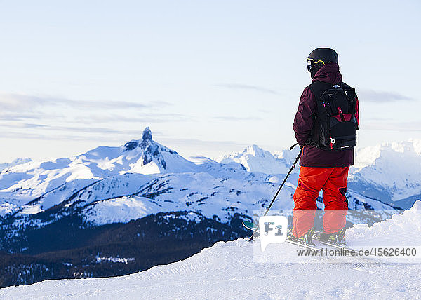 A lone skier stands on a ridge and looks off into the distance at the iconic Black Tusk at Whistler Blackcomb