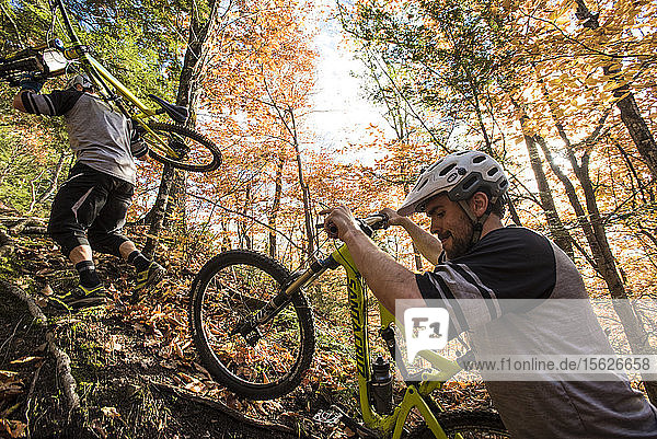 Mountainbiker tragen ihr Fahrrad bergauf in New Hampshire