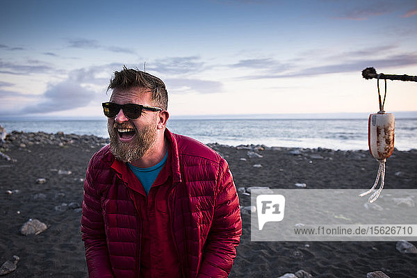 Mann lacht auf seinem Campingplatz in der Nähe des Ozeans an der verlorenen Küste