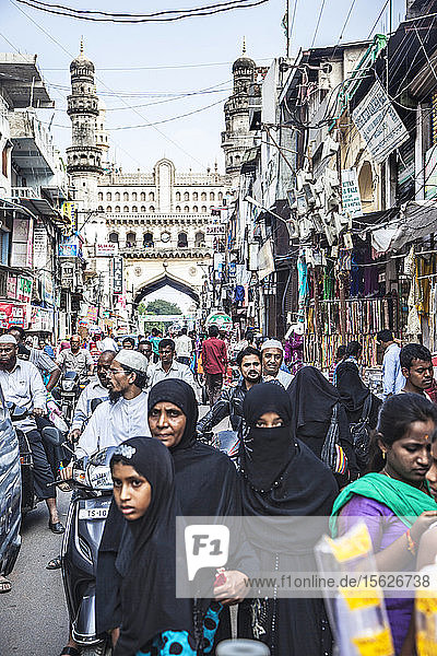 Burkha-Frauen gehen an belebten Straßen und einem Markt in der Nähe des Char Minar in Hyderabad  Indien  vorbei