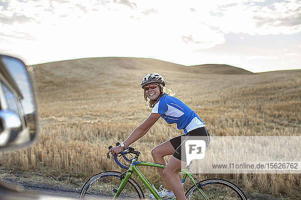 Eine lächelnde Frau fährt mit ihrem Rennrad durch die hügelige Landschaft des Palouse in Moskau  Idaho