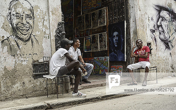 Men talk outside of an art shop in Havana  Cuba.