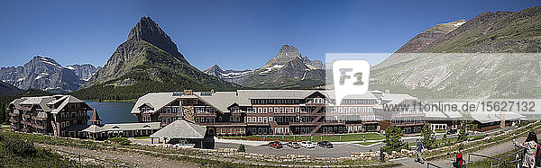 Panoramablick auf das Many Glacier Hotel unter einer Bergkette und am Swiftcurrent Lake im Glacier National Park in Montana.