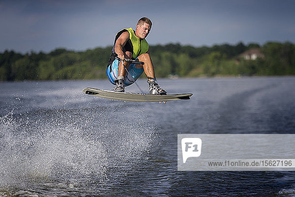 Foto eines Mannes in der Luft beim Wakeboarding auf einem Fluss