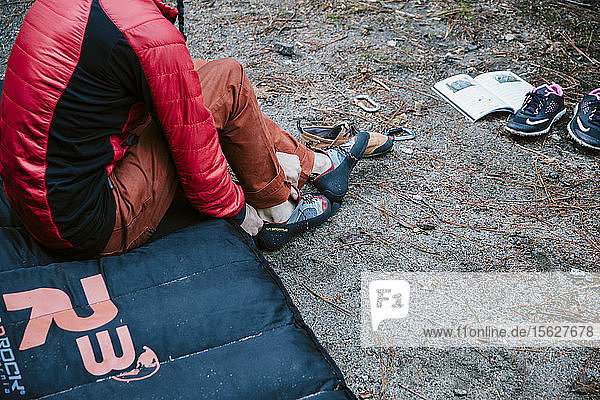 A man putting on his climbing shoes before bouldering in Yosemite Valley.