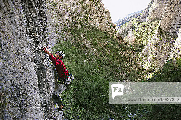 Foto eines abenteuerlustigen Mannes  der in der Kletterroute Cyclops (5.13a) in El Portero Chico  Monterrey  Mexiko  am Fels klettert