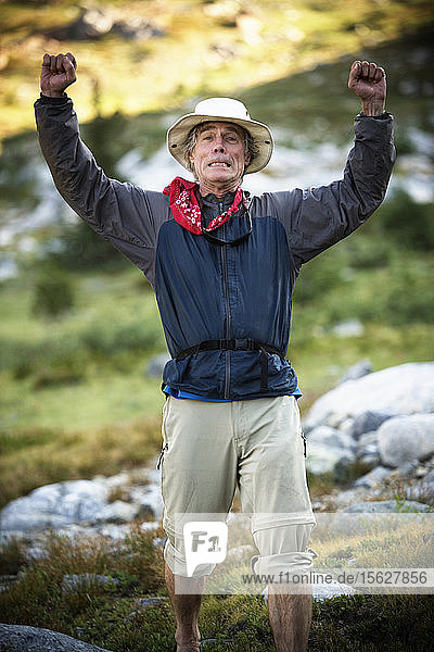 A mature male hiker with his arms raised in the Ansel Adams Wilderness  Sierra Nevada Mountains  California  USA.