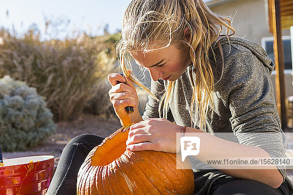 Ein junges Mädchen schnitzt an Halloween einen Kürbis