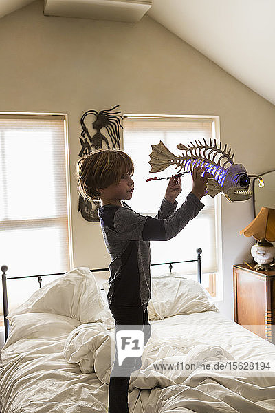 Sechsjähriger Junge spielt mit seinem Spielzeug auf seinem Bett