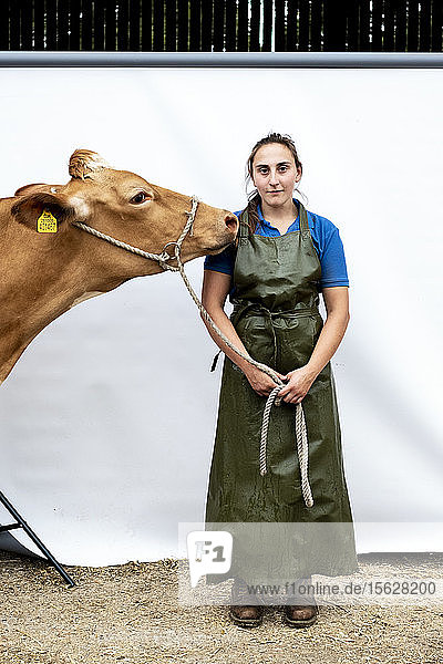 Porträt einer Bäuerin in grüner Schürze mit einer Guernsey-Kuh.