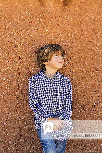 Porträt eines sechsjährigen Jungen an einer Lehmziegelmauer