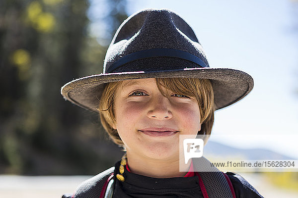 Porträt eines lächelnden sechsjährigen Jungen mit Fransen  der einen Hut trägt