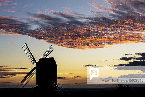 Windmühle bei Sonnenuntergang unter einem romantischen Wolkenhimmel.