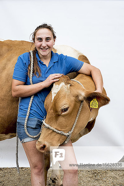 Porträt einer lächelnden Bäuerin mit einer Guernsey-Kuh.