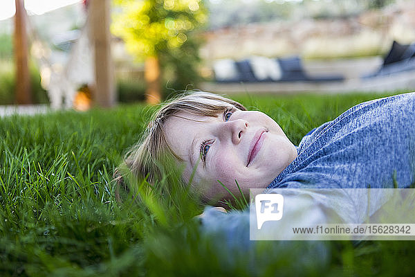 portrait of smiling Six year old boy lying down in green grass