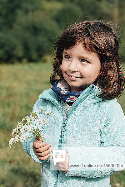 Porträt eines lächelnden kleinen Mädchens mit Wildblumen im Herbst