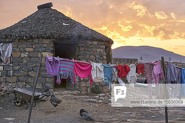 Sonnenuntergang an einem typischen Haus mit hängender Kleidung  Lesotho  Afrika