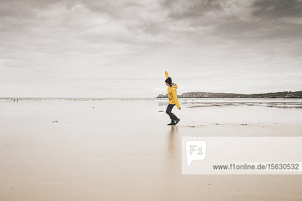 Young woman wearing yellow rain jacket at the beach  Bretagne  France