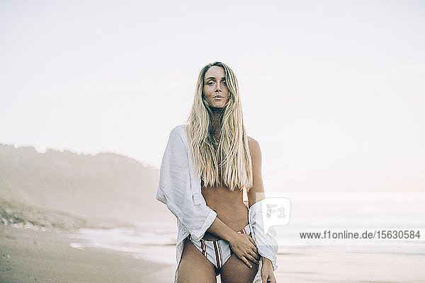 Young blond woman wearing bikini at the beach during sunrise