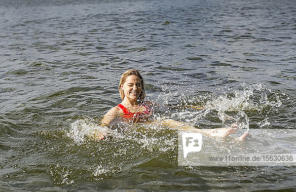 Lächelnde Frau planscht in einem See