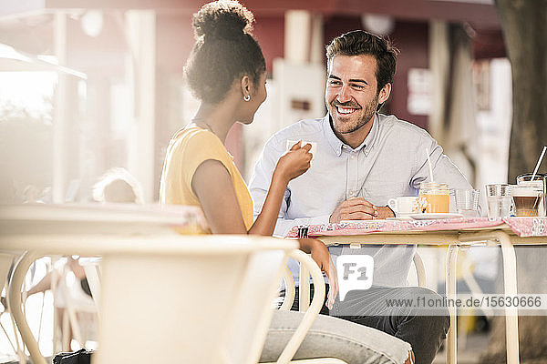 Glückliches junges Paar unterhält sich in einem Straßencafé