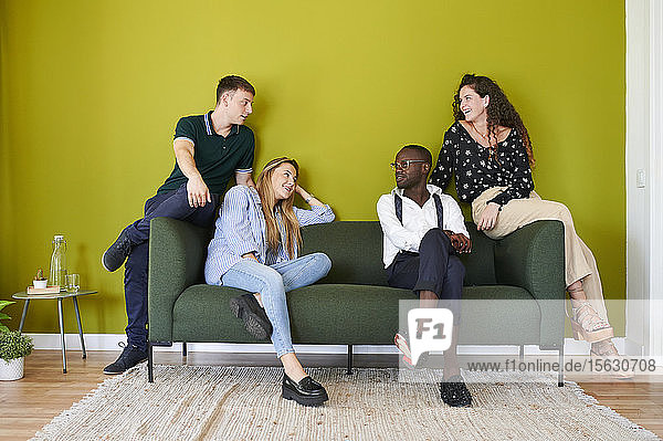 Gelegenheitskollegen unterhalten sich auf einem Sofa in einer grün ummauerten Bürolounge