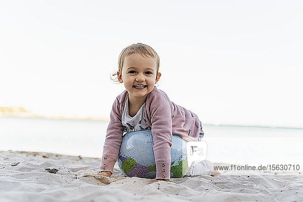 Porträt eines glücklichen kleinen Mädchens beim Spielen mit dem Earth-Beachball