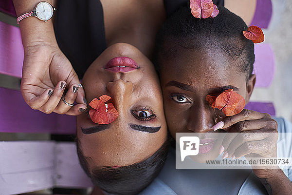 Porträt von zwei jungen Frauen  die mit Blumen Augen bedecken
