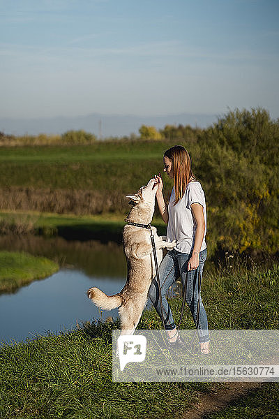 Young woman teaching her dog in nature