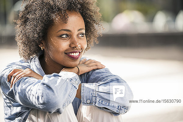 Porträt einer lächelnden jungen Frau  die sich im Freien entspannt