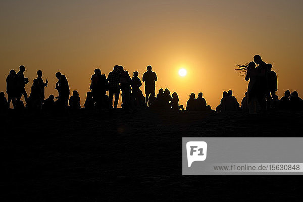 Portugal  Algarve  Silhouetten von Menschen  die sich am Kap Saint Vincent gegen die untergehende Sonne entspannen