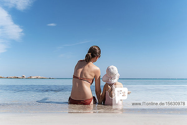 Rückansicht einer Mutter mit Tochter im Meer sitzend