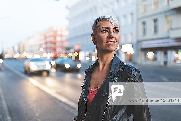 Porträt einer blonden Frau  die abends am Straßenrand steht  Berlin  Deutschland