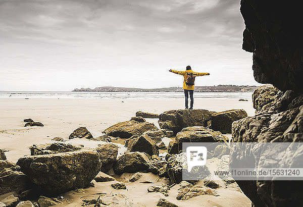 Young woman wearing yellow rain jacket at the beach at rock cave  Bretagne  France