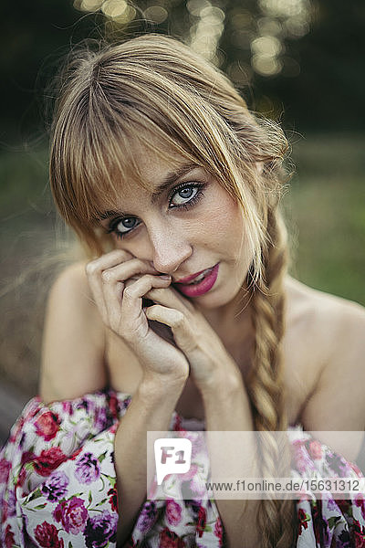 Porträt einer jungen blonden Frau mit Zopf im Sommer